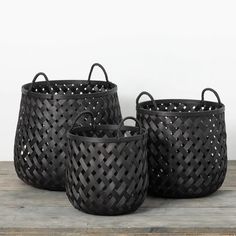 three black baskets sitting on top of a wooden table