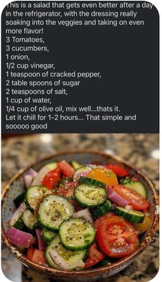 a bowl filled with cucumbers and tomatoes on top of a counter next to a recipe