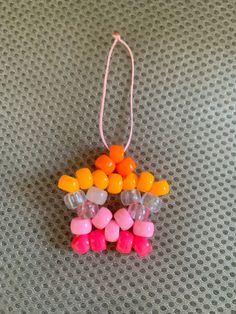 an ornament made out of candy on top of a gray surface with pink, orange and yellow candies