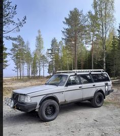 an off - road vehicle parked on the side of a dirt road in front of trees