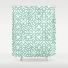 a green and white shower curtain with snowflakes on the bottom, in an abstract pattern