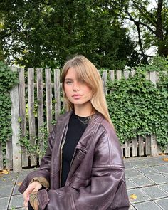 a woman standing in front of a fence with her hand on her hip and looking at the camera