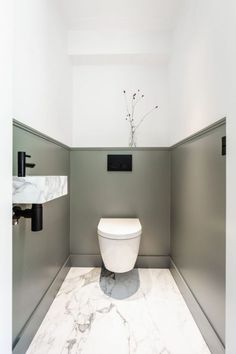 a white toilet sitting inside of a bathroom next to a wall mounted faucet