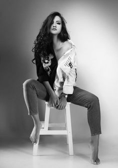 a woman sitting on top of a white chair in black and white photo studio posing for the camera