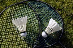 two tennis racquets sitting on top of a green grass covered field next to each other