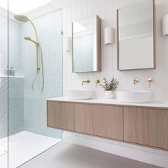 a bathroom with two sinks, mirrors and a shower head mounted to the side of the wall