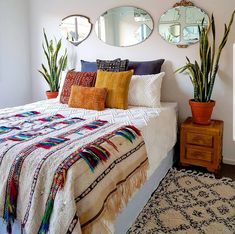 a bed sitting in a bedroom next to two planters and mirrors on the wall