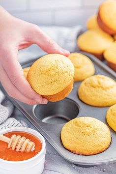 a person is holding a muffin in front of some cupcakes on a tray