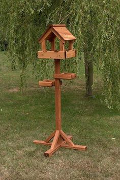 a wooden bird house on a stand in the grass