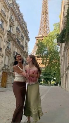 two women standing next to each other in front of the eiffel tower