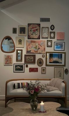 a living room filled with lots of framed pictures on the wall above a coffee table