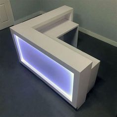 an illuminated reception table in the middle of a room with black flooring and white walls