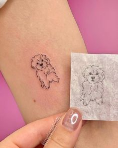 a small dog tattoo on the back of a woman's left arm, next to a piece of paper