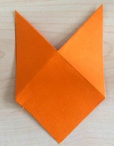 an orange origami bird sitting on top of a wooden table