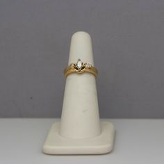 a gold ring with two diamonds on it sitting on top of a white display stand