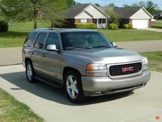 a silver suv parked on the side of a road in front of some grass and houses