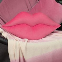 a pink and white blanket sitting on top of a black chair next to a pillow