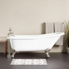 a white bath tub sitting on top of a hard wood floor next to a rug