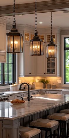 a kitchen island with stools and lights hanging from it