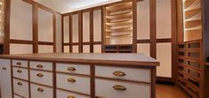 an empty room with many drawers and cupboards in the center, along with wooden shelves