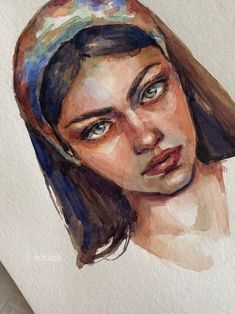 a watercolor painting of a woman's face with blue eyes and brown hair