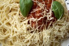 a plate of spaghetti with sauce and spinach leaves