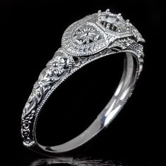 an antique style engagement ring with filigrees on the sides and floral details