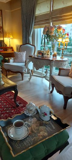 a living room filled with furniture and a large window covered in curtains, sitting next to a coffee table