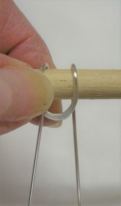 a hand holding a piece of wood with two metal pins attached to the end of it