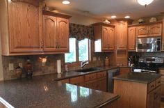 a large kitchen with wooden cabinets and granite counter tops, along with stainless steel appliances