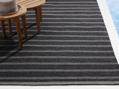 a black and white striped rug next to a pool with a wooden table on it