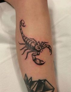 a scorpion tattoo on the leg of a person with an origami in front of it