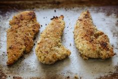 three pieces of chicken sitting on top of a pan