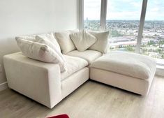 a white couch sitting in front of a large window next to a red rug on top of a hard wood floor