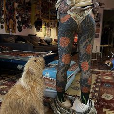 a dog sitting next to a woman's leg in a room filled with furniture