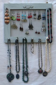 a white frame with many necklaces hanging on it