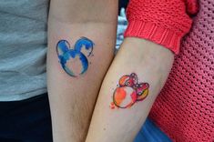 two people with matching tattoos on their arms, one is holding the other's arm