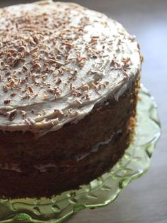 a cake with white frosting and nuts on top sitting on a green glass plate