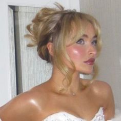 a woman with blonde hair wearing a white dress and posing for the camera in front of a mirror