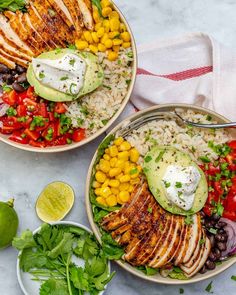 two bowls filled with chicken, rice and veggies on top of a table