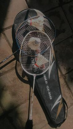 two badminton rackets sitting on top of a tennis racquet