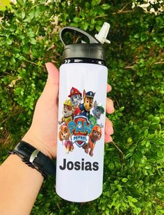 someone holding up a water bottle with the name josias on it in front of some bushes