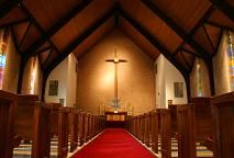 the inside of a church with pews and stained glass windows on either side of the aisle