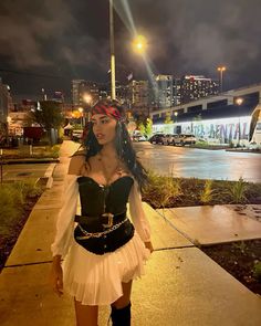 a woman wearing a pirate costume standing on a sidewalk