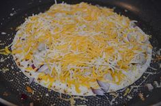 a pizza with cheese and onions in a frying pan on the stove top, ready to go into the oven