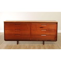 a wooden dresser sitting on top of a hard wood floor next to a white wall