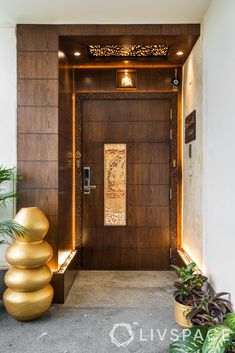 the entrance to an apartment building with large gold balls on the floor and planters in front