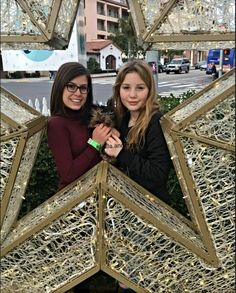 two girls standing in front of a star sculpture