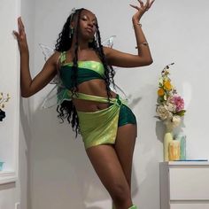 a woman in a green and yellow outfit is standing on one leg with her hands up