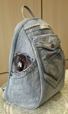 a denim backpack with some glasses in it